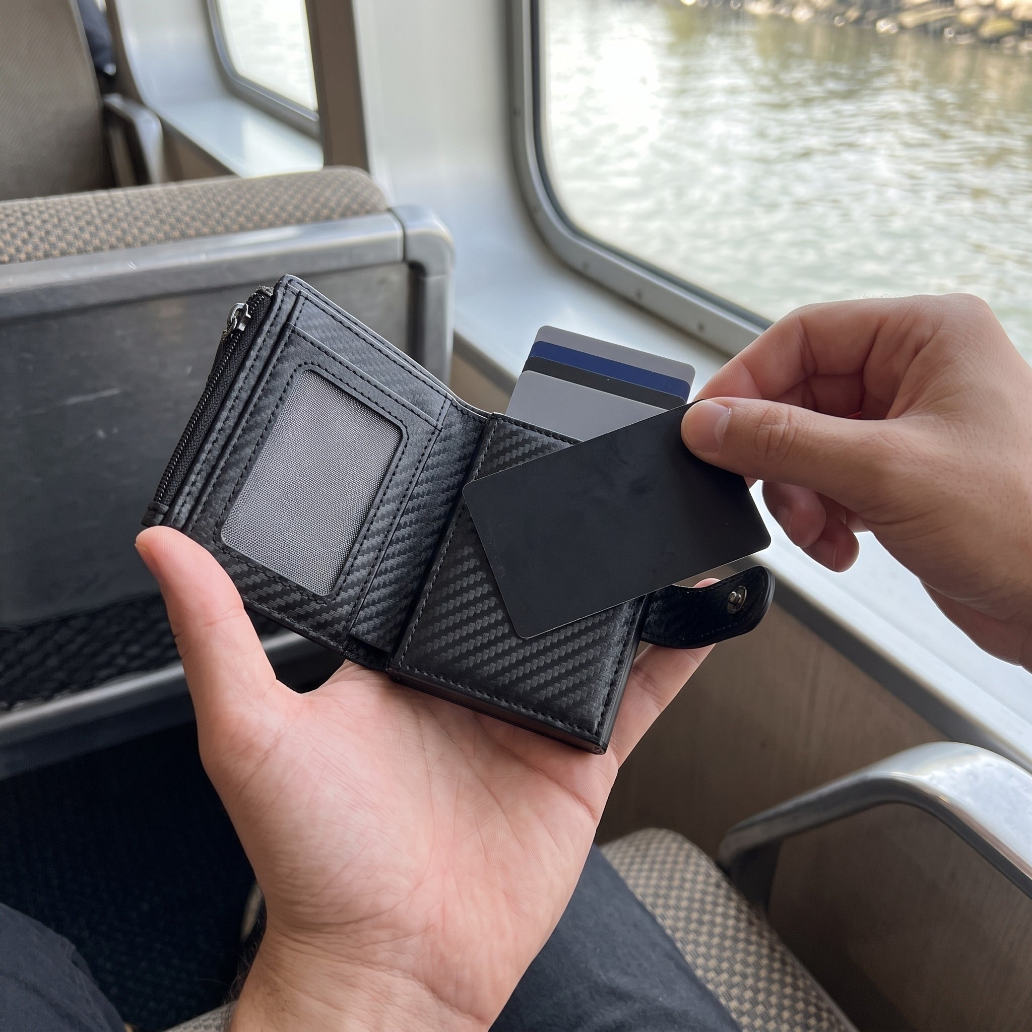 Card selected from carbon-pattern wallet on a train