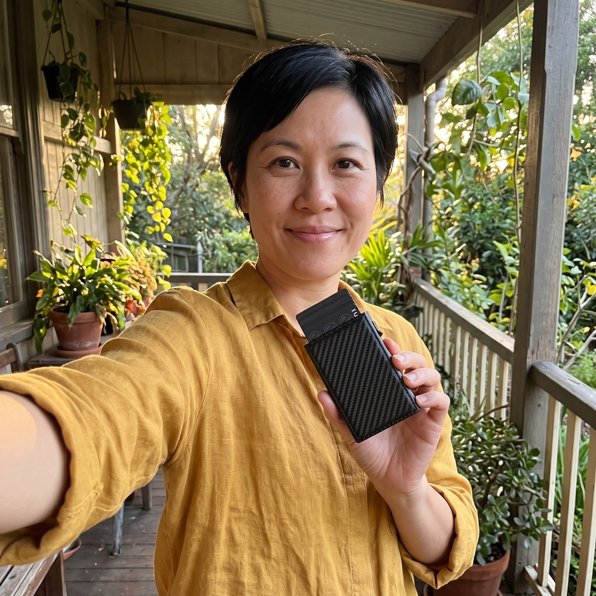 Short-haired woman holding black wallet on a porch