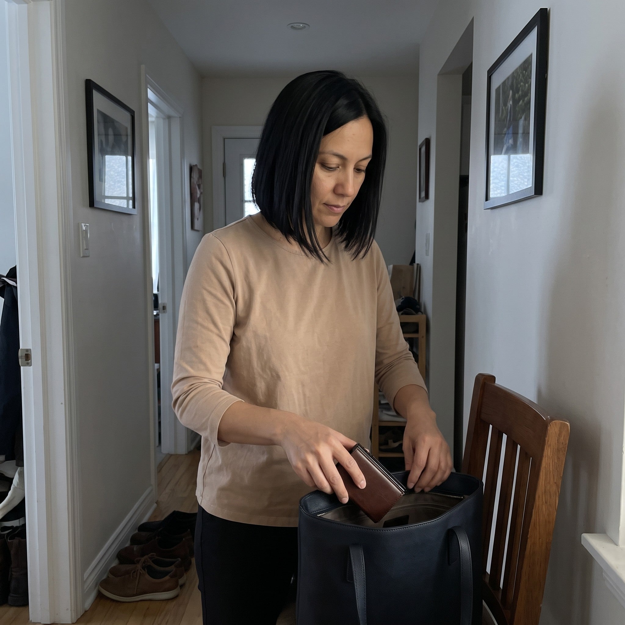 Sophie packing her brown wallet in a work tote at home