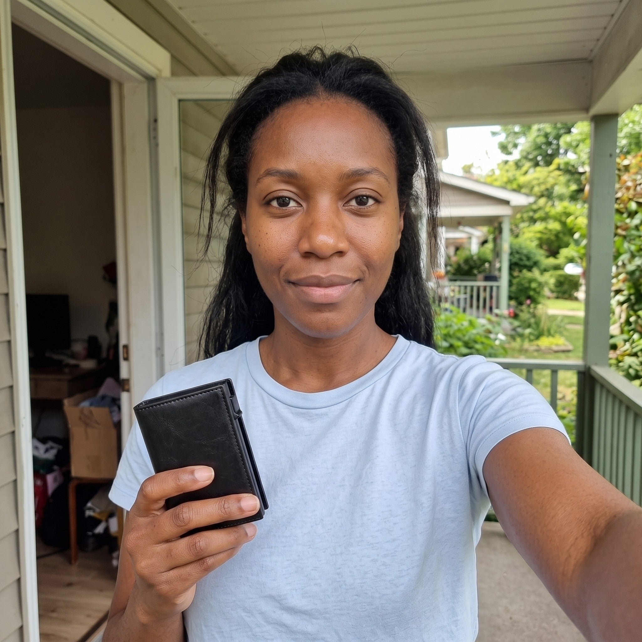 Priya holding a black wallet on her porch
